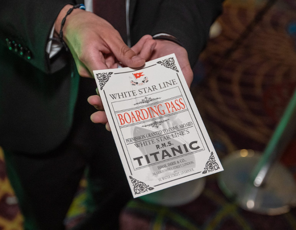 Na zdjeciu mężczyzna podający kartę - bilet na "Titanica", widać tylko jego dłonie