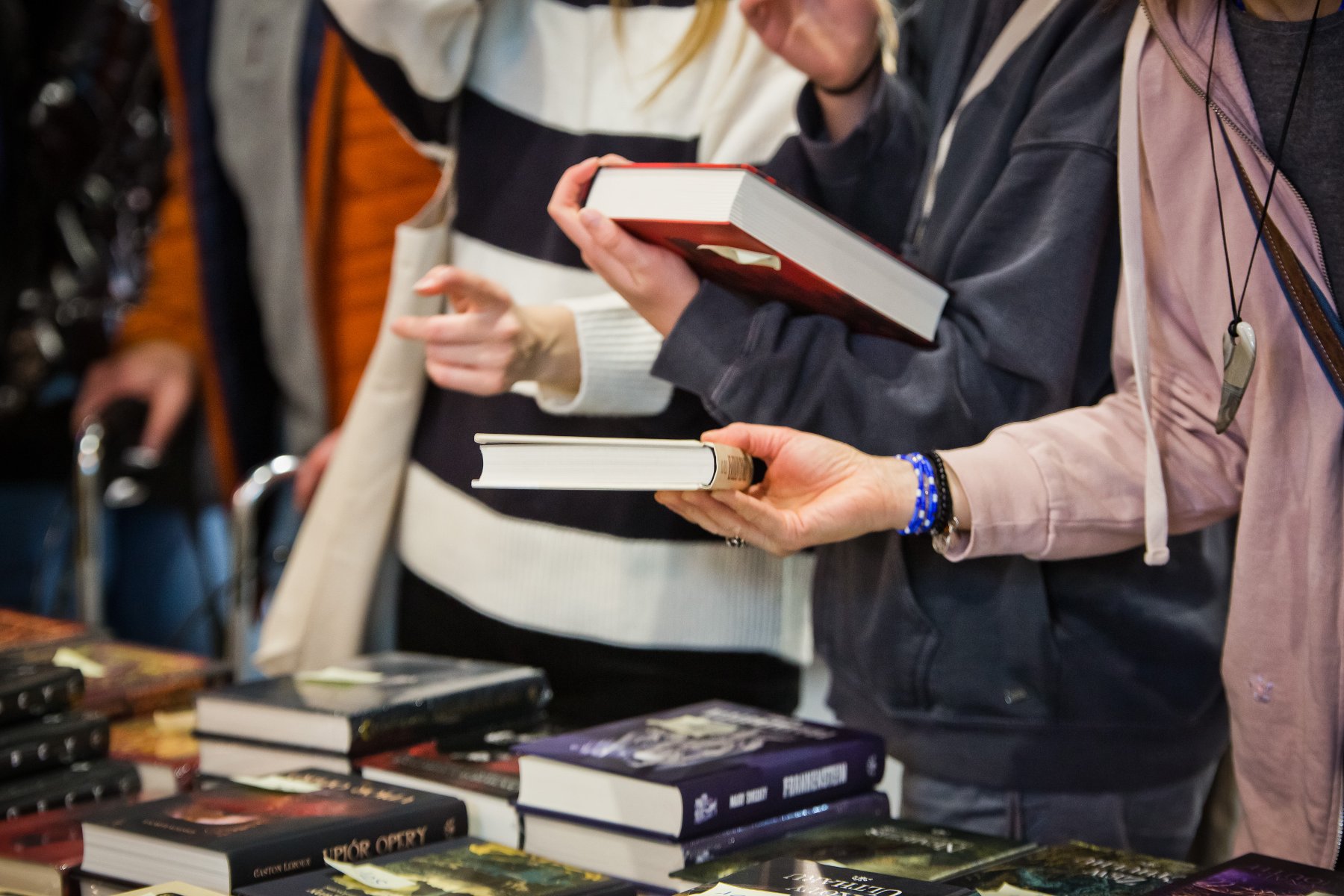 Na zdjęciu osoby trzymające książki