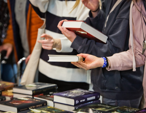 Na zdjęciu osoby trzymające książki