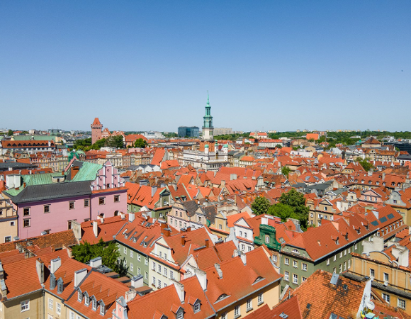 Na zdjęciu panorama Poznania, widać czerwone dachy kamienic i wieżę Ratusza