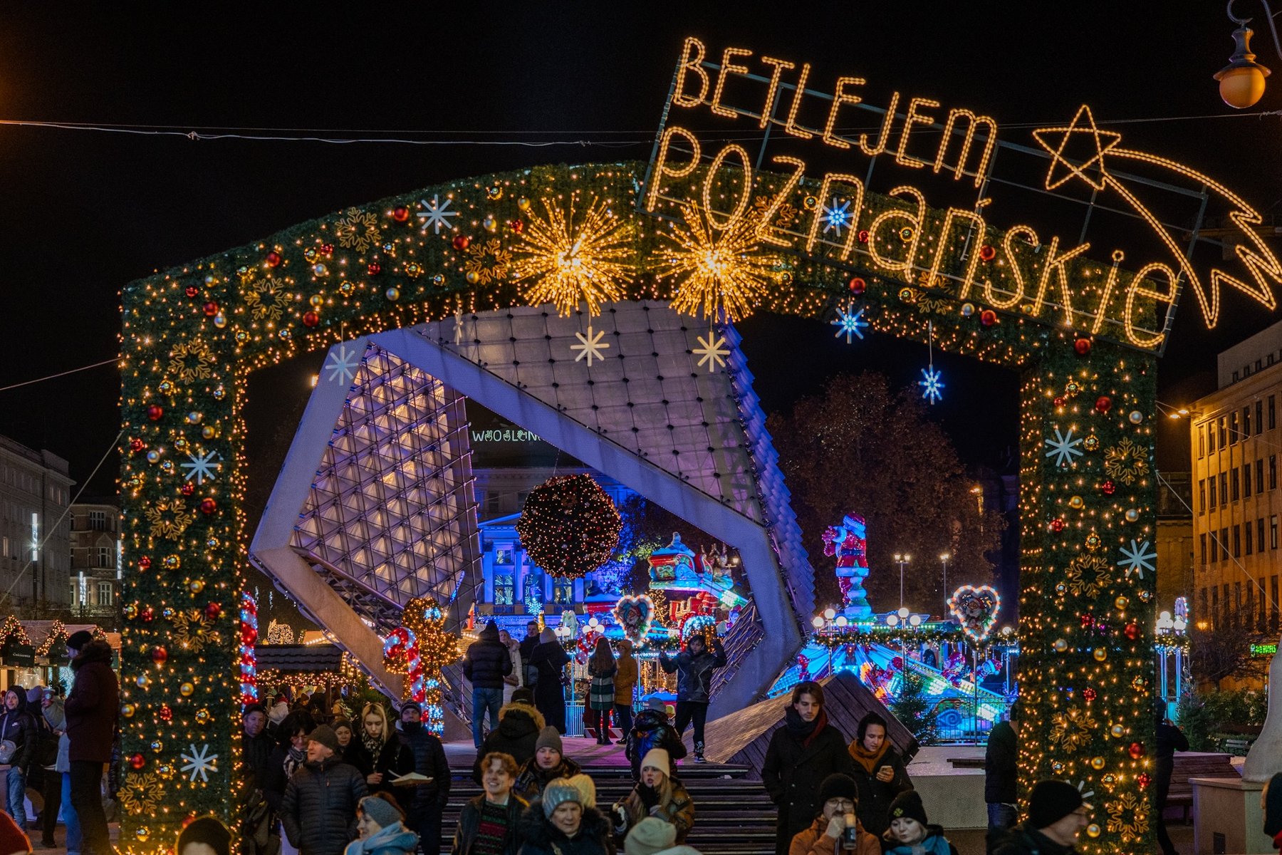 Na zdjęciu podświetlona fontanna na placu, nad nią napis: betlejem poznańskie