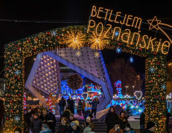 Na zdjęciu podświetlona fontanna na placu, nad nią napis: betlejem poznańskie