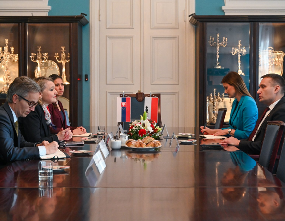 Na zdjęciu reprezentacyjna sala, w niej, przy dużym stoke, siedzi pięć osób, w centrum flagi Polski i Słowacji