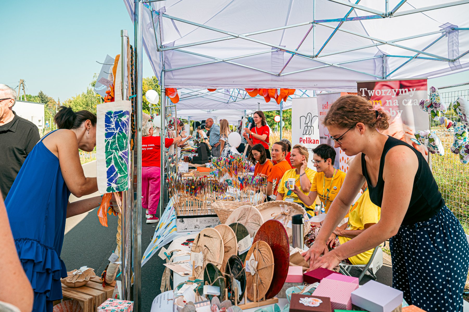Na zdjęciu stoisko, po obu stronach ludzie, w tle banery organizacji pozarządowych