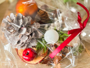 Na zdjęciu stroik świąteczny owinięty w folię, z kokardą