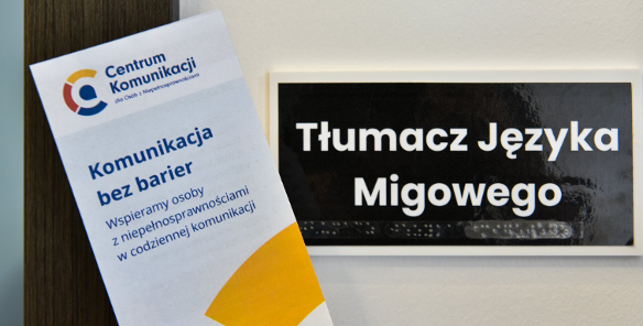 Na zdjęciu tabliczka z napisem Tłumacz języka migowego i ulotka centrum komunikacji trzymana w dłoni
