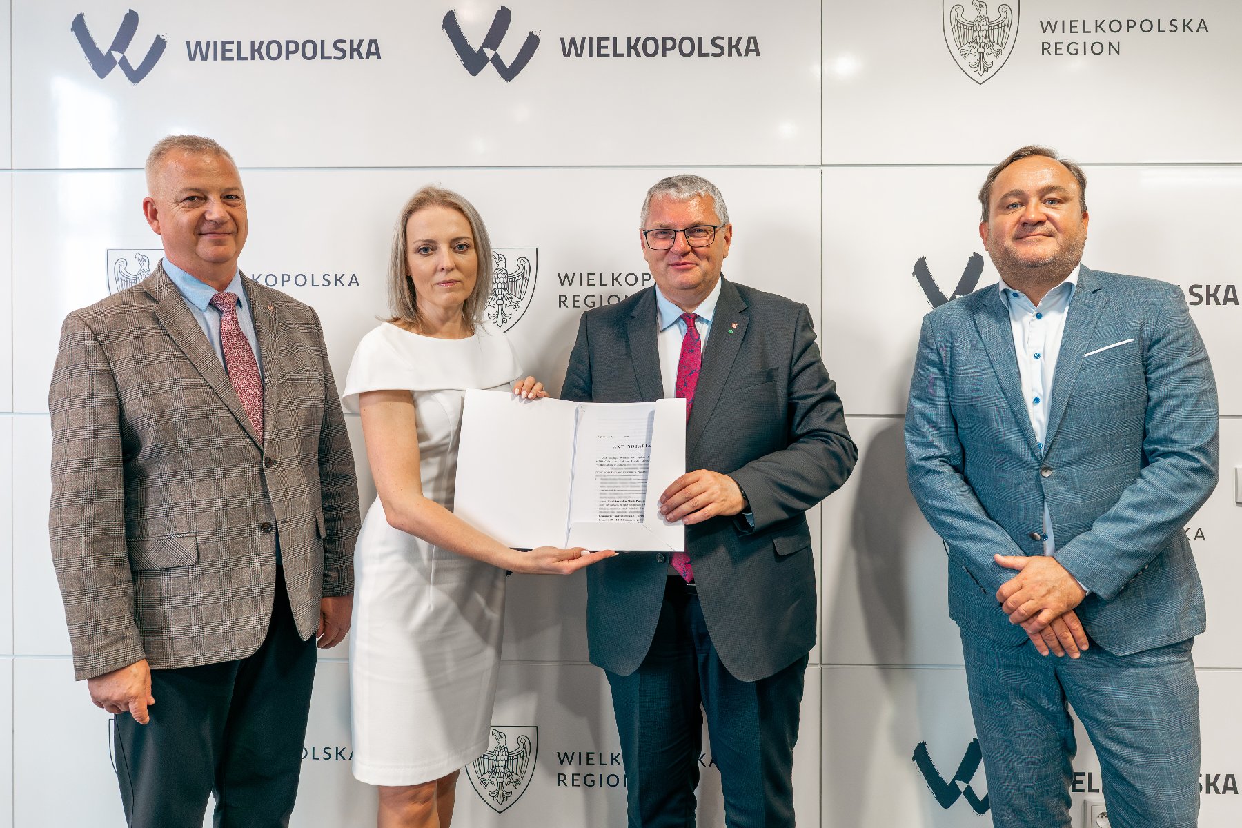 Na zdjeciu trzech mężczyzn i kobieta, prezentują akt notarialny