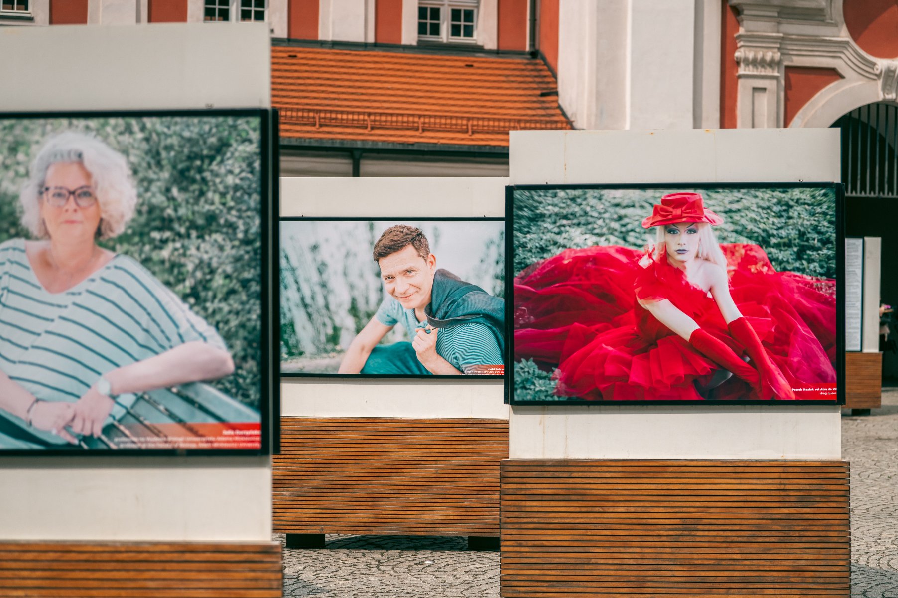 Na zdjęciu trzy fotografie na wystawie, w tle budynek urzędu miasta