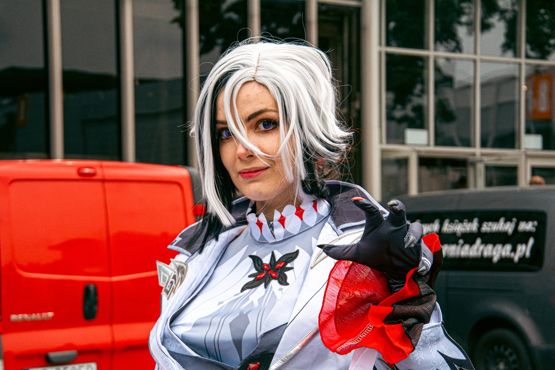 Na zdjeciu uśmiechnięta cosplayerka, w tle bramka z napisem: miłego Poznania