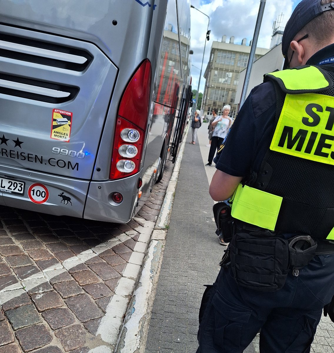 Na zdjęciu widać strażnika miejskiego, który rozmawia z kierowcą autokaru - sprawca uszkodzenia znaku na alejach Marcinkowskiego