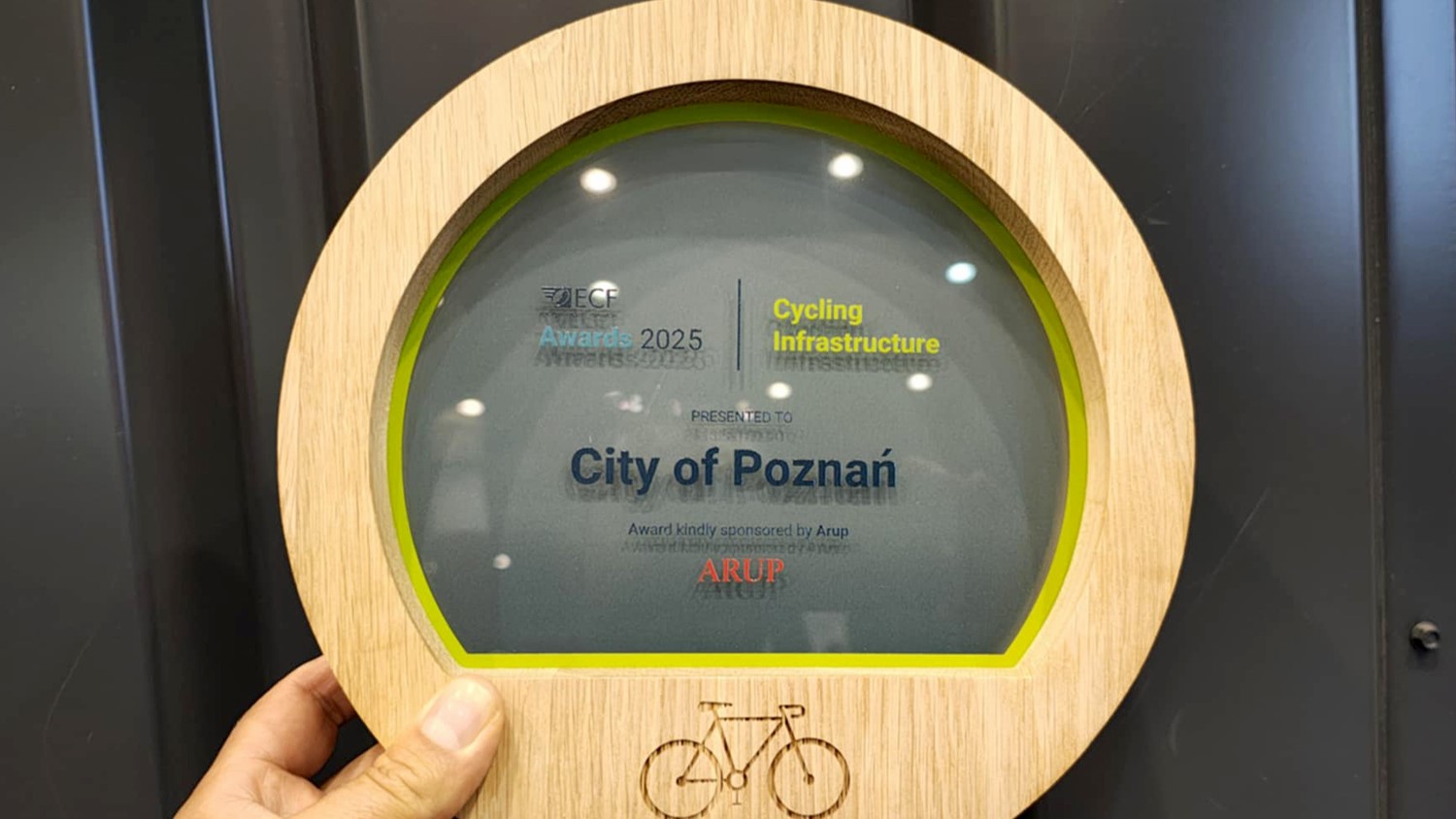 Nagroda przyznana przez Europejską Federację Cyklistów ECF Award w kategorii Infrastruktura Rowerowa. Drewniana okrągła ramka z rysunkiem roweru, w środku szkło z napisami, które informują o nagrodzie..