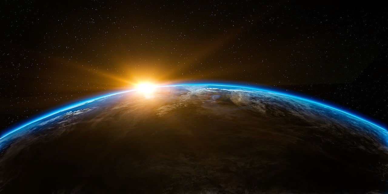 Obrazek przedstawia wschodzące słońce nad planetą Ziemią.