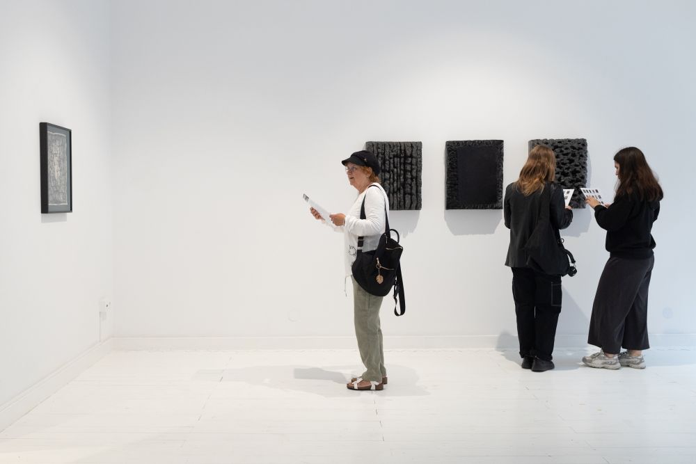 Odwrócona tyłem do fotografa osoba w kolorowej kurtce ogląda jeden z obiektów na wystawie.