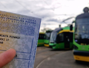 Osoba trzyma dowód rejestracyjny samochodu. W tle widać tramwaje
