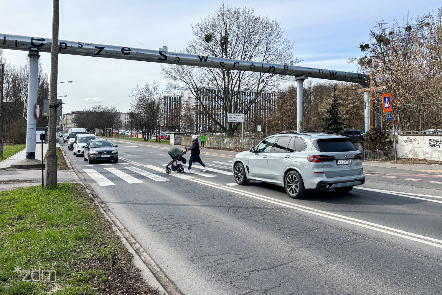 Osoba z wózkiem przechodząca przez przejście dla pieszych przy ul. Dolna Wilda. Przed przejściem, z obu stron zatrzymały się samochody