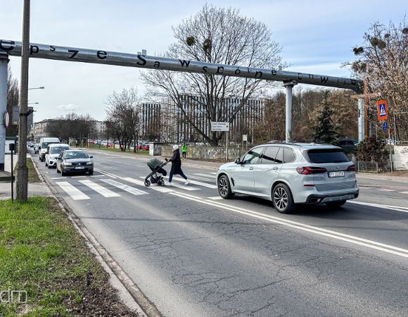 Osoba z wózkiem przechodząca przez przejście dla pieszych przy ul. Dolna Wilda. Przed przejściem, z obu stron zatrzymały się samochody
