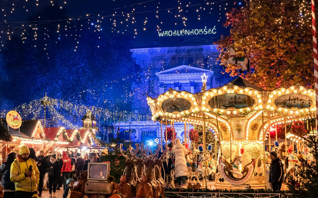 Plac Wolności z karuzelą i jarmarkiem, w tle świąteczne dekoracje.
