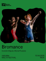 W centralnej części, wewnątrz nieregularnego wycięcia, widnieje zdjęcie dwóch mężczyzn w strojach zapaśniczych (czerwonym i niebieskim), którzy stoją na scenie w pozach z uniesionymi rękami jakby strzelali z łuku. Całość znajduje się na intensywnie zielonym tle. Na dole umieszczono czarne napisy. Są to szczegóły wydarzenia zawarte w treści artykułu.