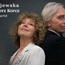 Dwie osoby stojące plecami do siebie na tle szarej, fakturowanej ściany. Po lewej stronie znajduje się kobieta w jasnym stroju z ozdobną broszką, po prawej mężczyzna w ciemnym garniturze. Obok informacje o artystach zawarte w treści artykułu oraz napis "Jubileusz".