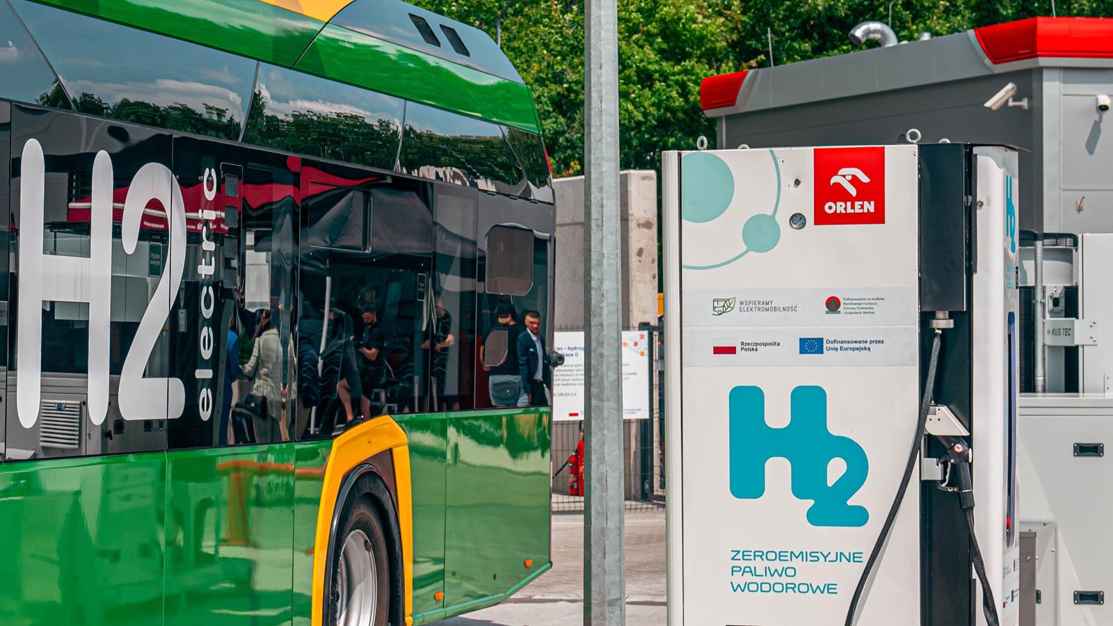 Po lewej zielony autobus wodorowy na stacji Orlen, po prawej dystrybutor wodoru