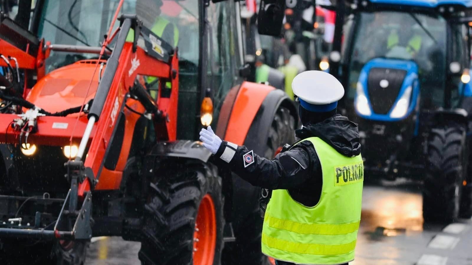 Policjantka w żółtej kamizelce sterująca ruchem ciągników podczas protestu rolników