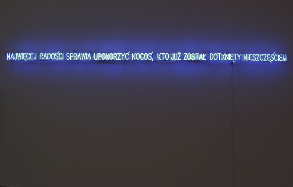 Portret mężczyzny ułożony z neonowych linii i kształtów, podświetlony na czerwono-pomarańczowo.