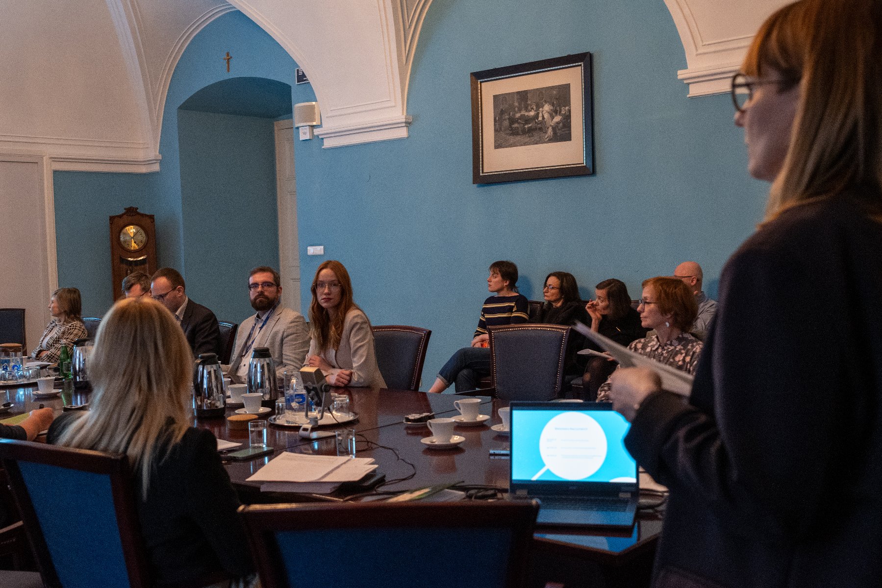 Posiedzenie komisji. Radni siedzą przy jednym podłużnym stole.