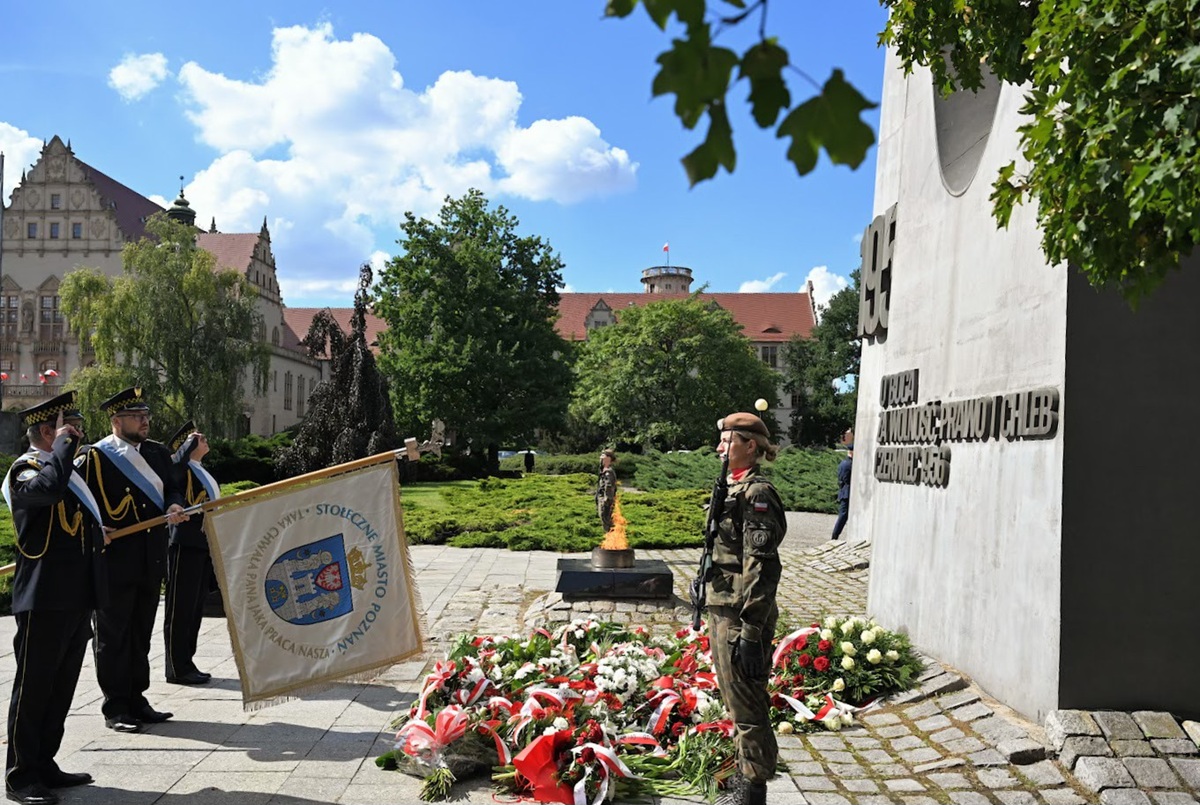 Przed pomnikiem Poznańskiego Czerwca 1956 wartę pełnią żołnierze, prze pomnikiem złożone wiązanki kwiatów, przed pomnikiem stoi poczet sztandarowy Straży Miejskiej ze sztandarem Poznania