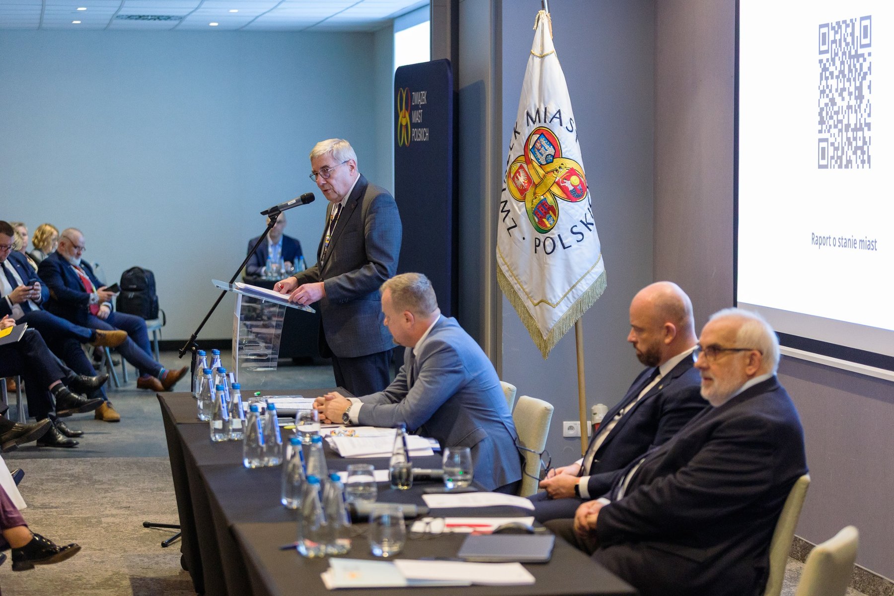 Przemawiający przed delegatami przewodniczący rady miasta.