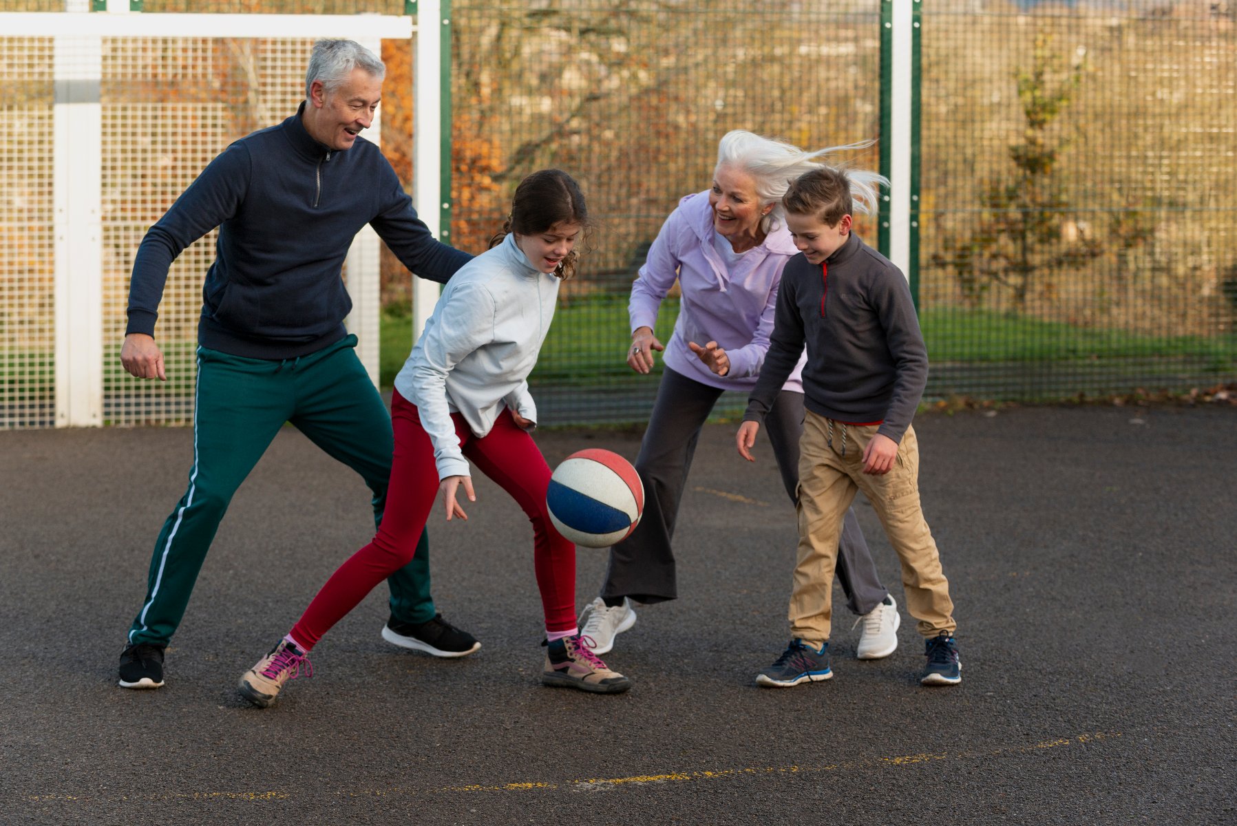 Rodzinna gra w koszykówkę - dwoje starszych osób i dwoje dzieci w trakcie kozłowania piłką