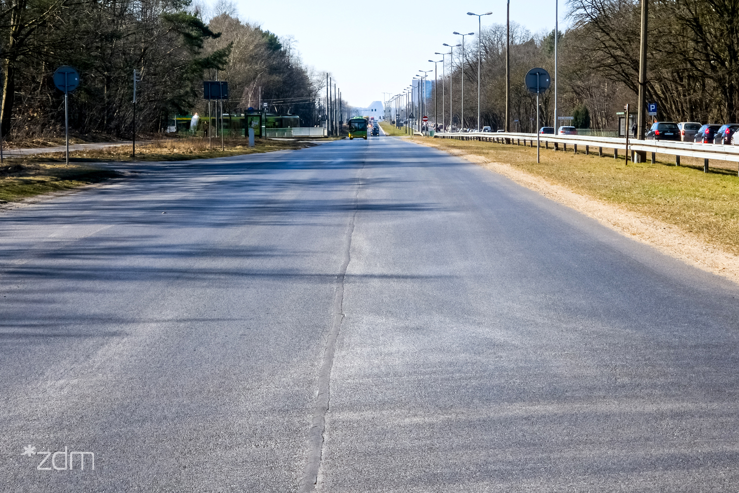 Równa asfaltowa nawierzchnia ul. Warszawskiej po remoncie, po bokach zieleń