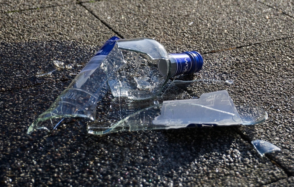 rozbita butelka po alkoholu leży na chodniku