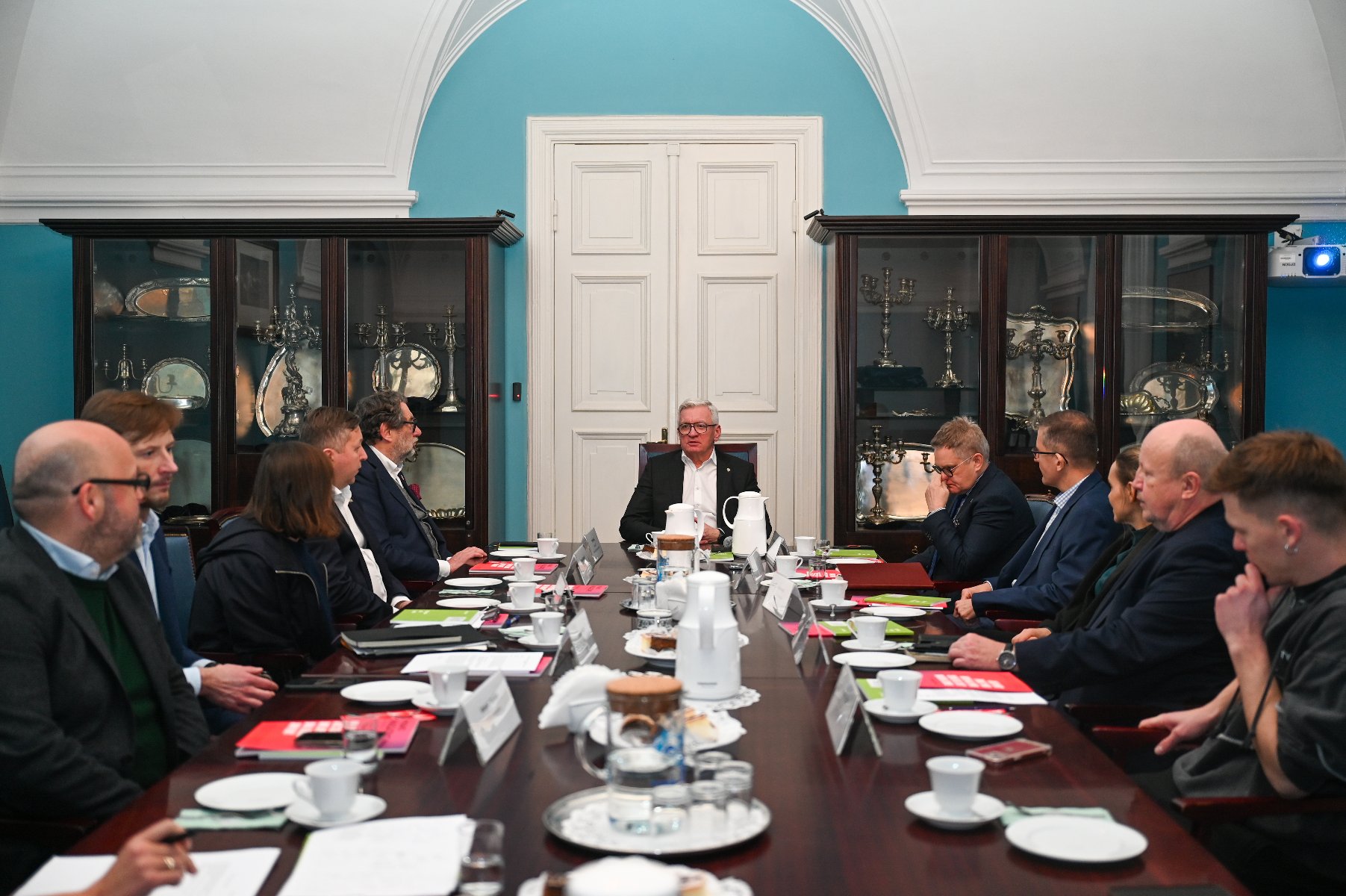 Sala Błękitna. Przy długim, ciemnym stole siedzi prezydent Jaśkowiak a dookoła stołu zaproszeni goście - ekspertki i eksperci Rady Mentorskiej.