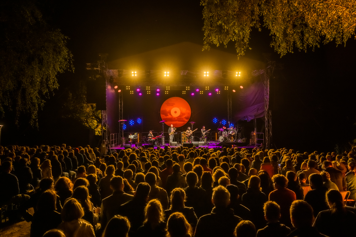 Scena w półmroku, na niej muzycy, przed sceną tłum zasłuchanej publiczności