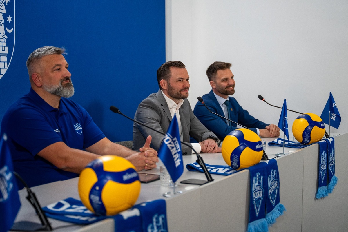 trzech mężczyzn siedzi za stołem podczas konferencji prasowej, na stole leżą piłki do siatkówki