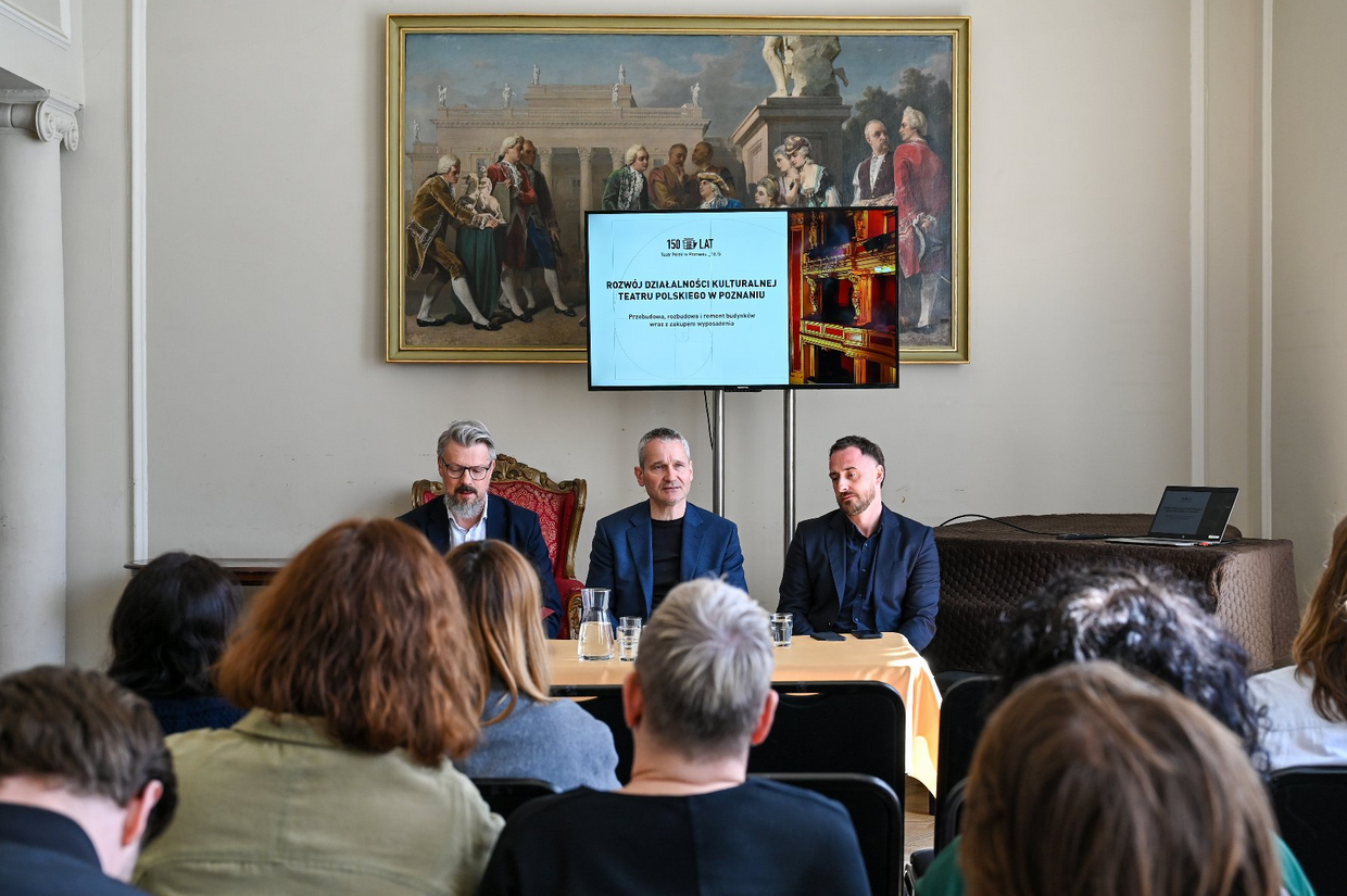 trzech mężczyzn siedzi za stołem podczas konferencji prasowej, przed nimi siedzą dziennikarze - grafika artykułu