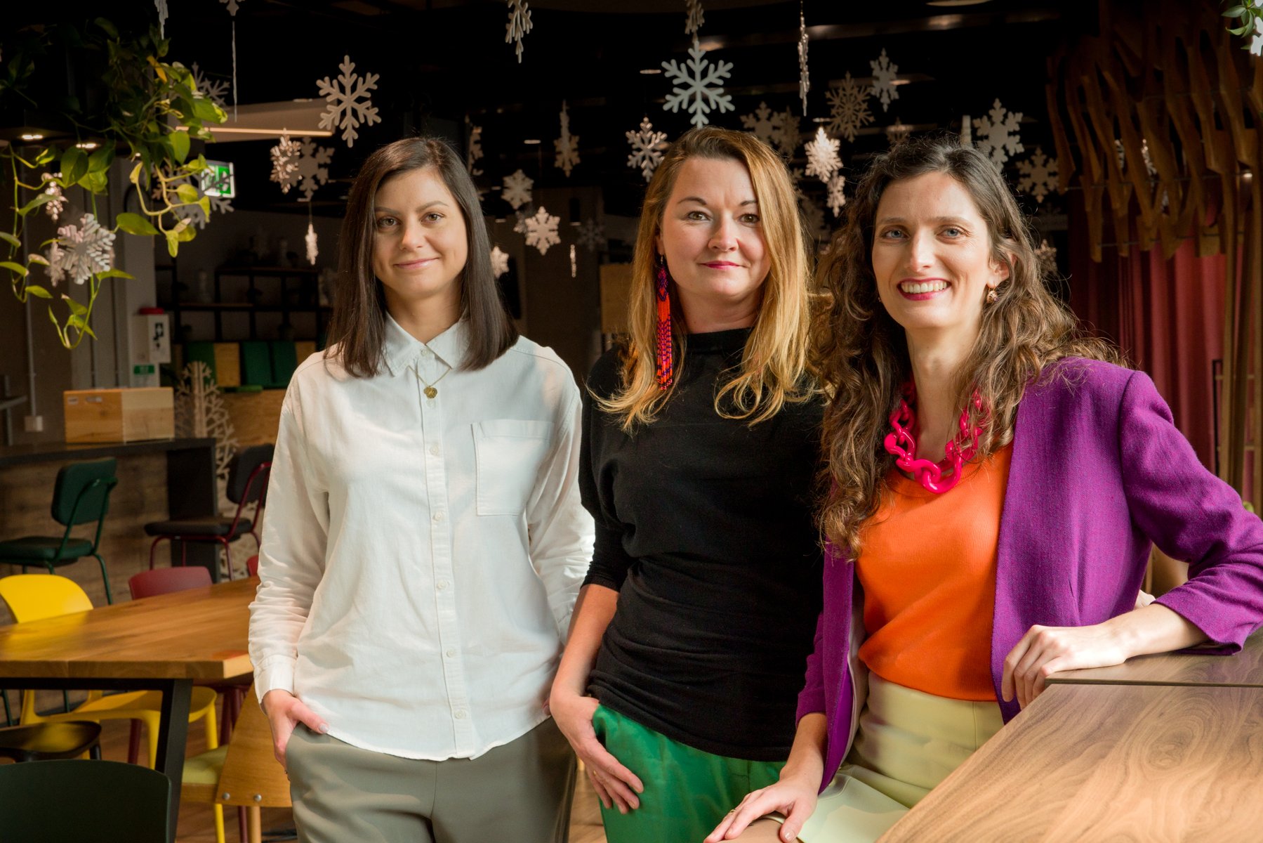 Trzy uśmiechnięte kobiety pozują razem na zdjęciu.