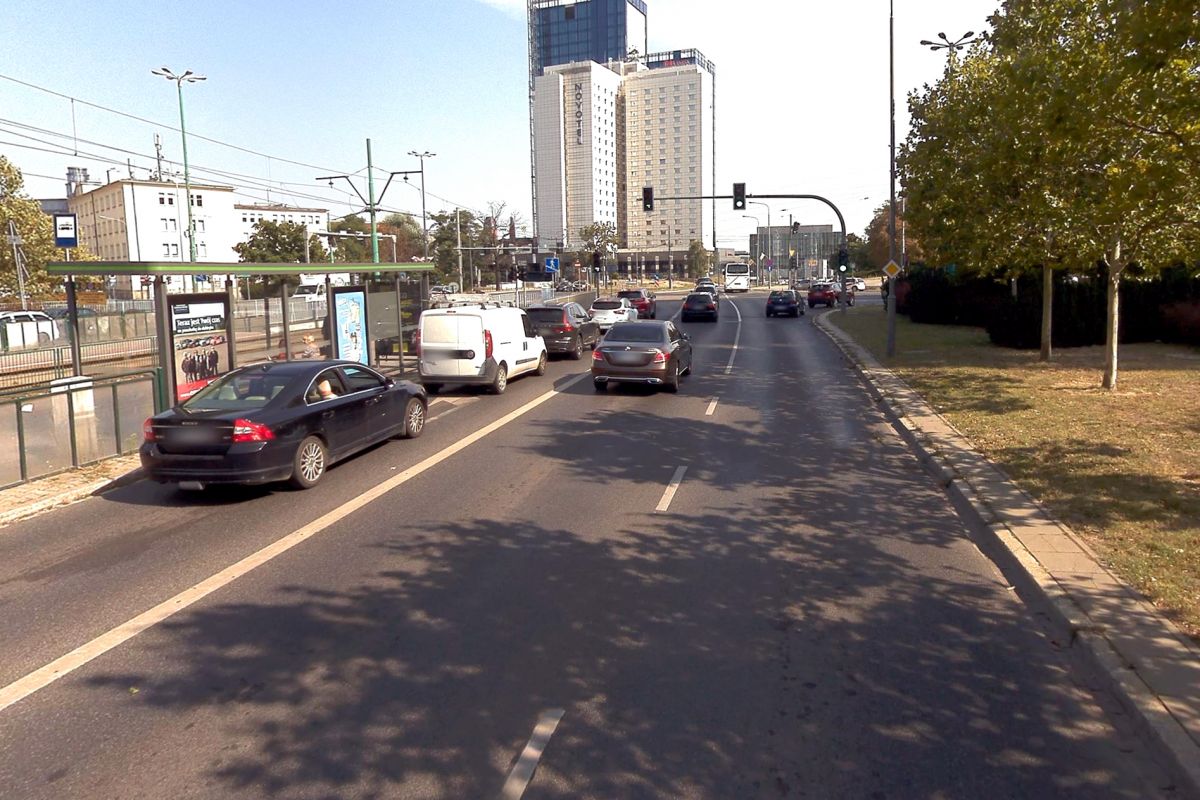 Ulica Matyi. Auta stoją na światłach przed skrzyżowaniem. W tle wysoki budynek hotelu Novotel