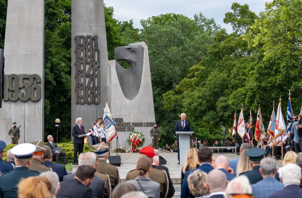 uroczystości przed pomnikiem Poznańskiego Czerwca 1956, uczestnicy stoją ze sztandarami, jedna osoba przemawia