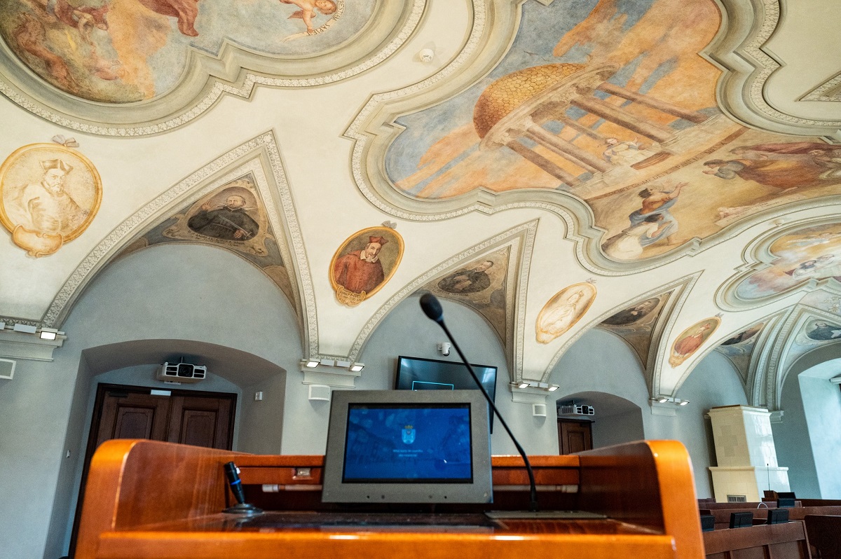 widok na salę sesyjną Rady Miasta Poznania z perspektywy mównicy z widocznym monitorem i mikrofonem - grafika artykułu