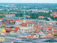 Widok z góry na panoramę Poznania z wyraźnie widoczną wieżą Ratusza na Starym Rynku oraz wieżami Katedry w tle po prawej stronie.