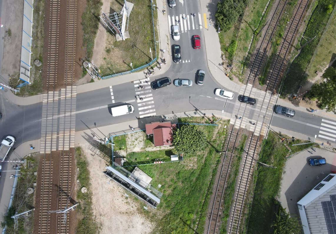 widok z góry na podwójny przejazd kolejowy, przez tory przejeżdżają samochody