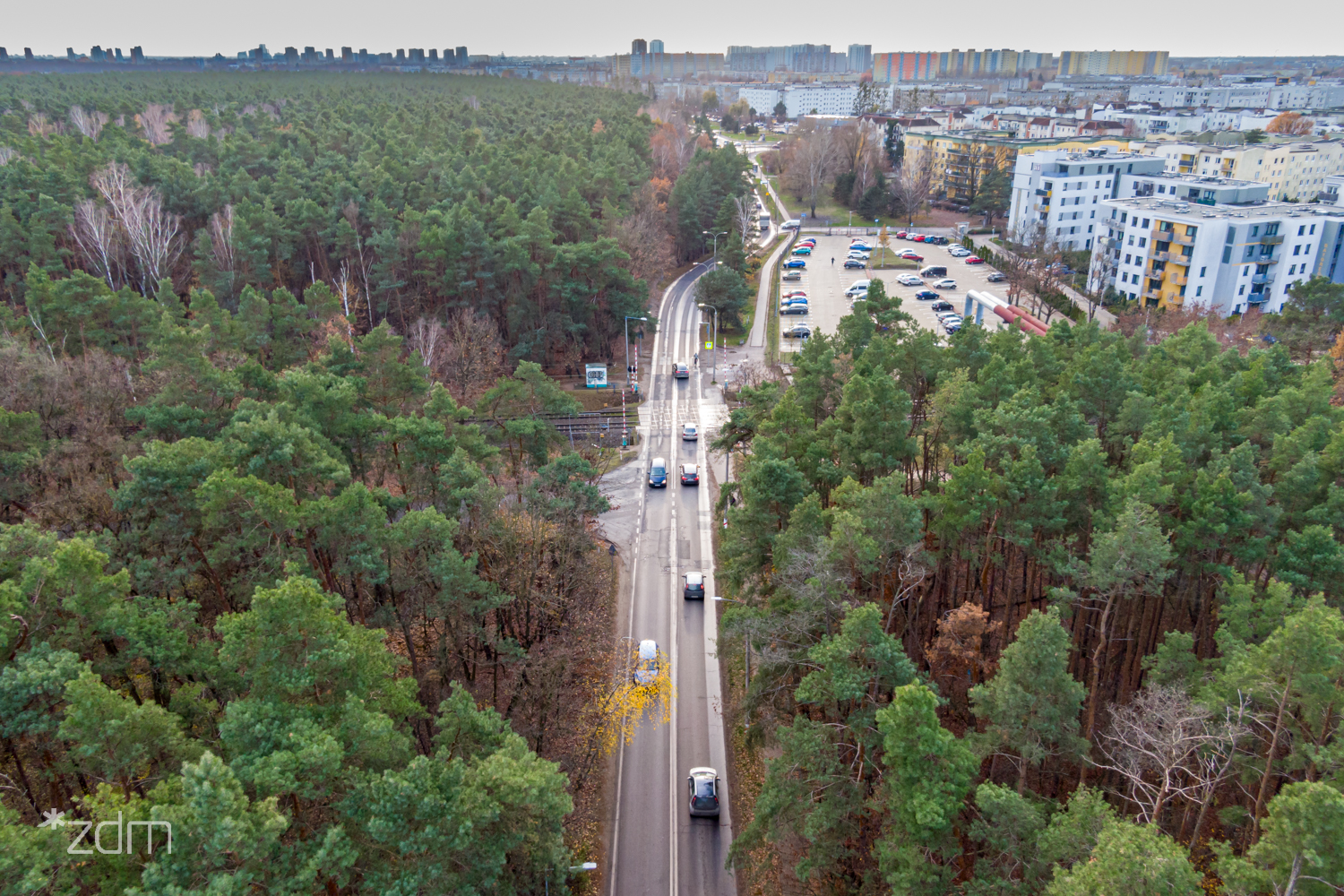 Widok z lotu ptaka na ul. Umultowską i samochody przejeżdżające przez przejazd kolejowy. Po prawej widać osiedle Batorego, a po lewej Las Żurawiniec