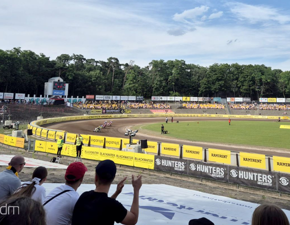 Widok z trybum na stadion żużlowy i ścigających się żużlowców