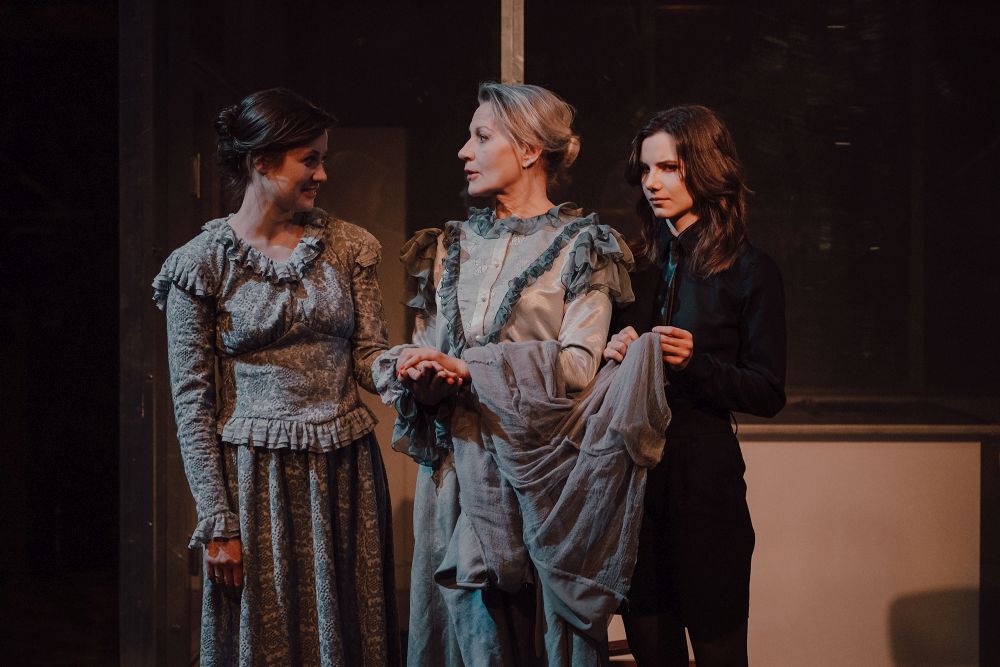 Wielki dinozaur (aktor w kostiumie) szuka ukrytego pod sceną nagiego chłopaka.