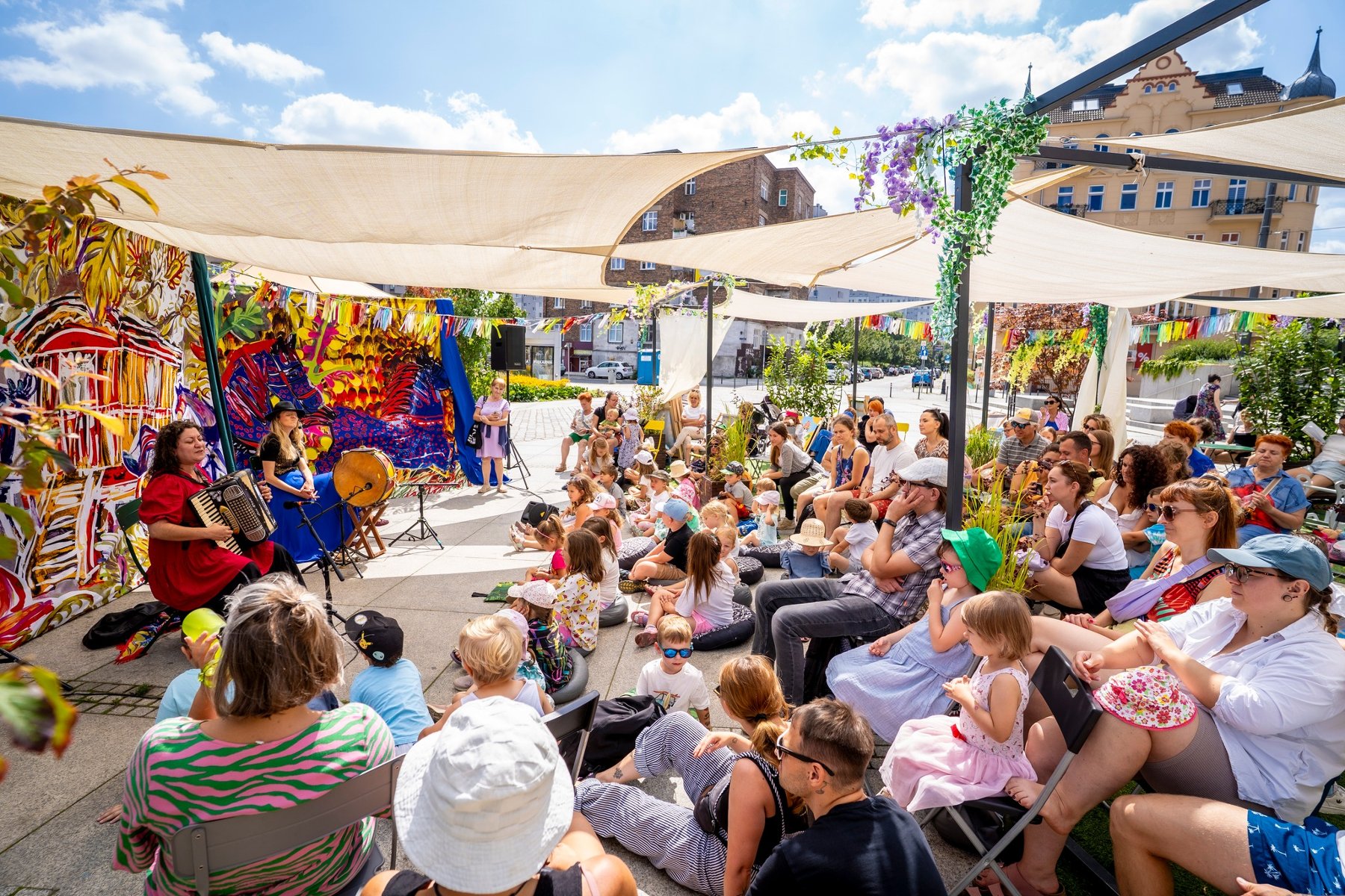 Występ muzyczny na Rynku Łazarskim. Kobieta grająca na akordeonie siedzi na krześle przed publicznością.