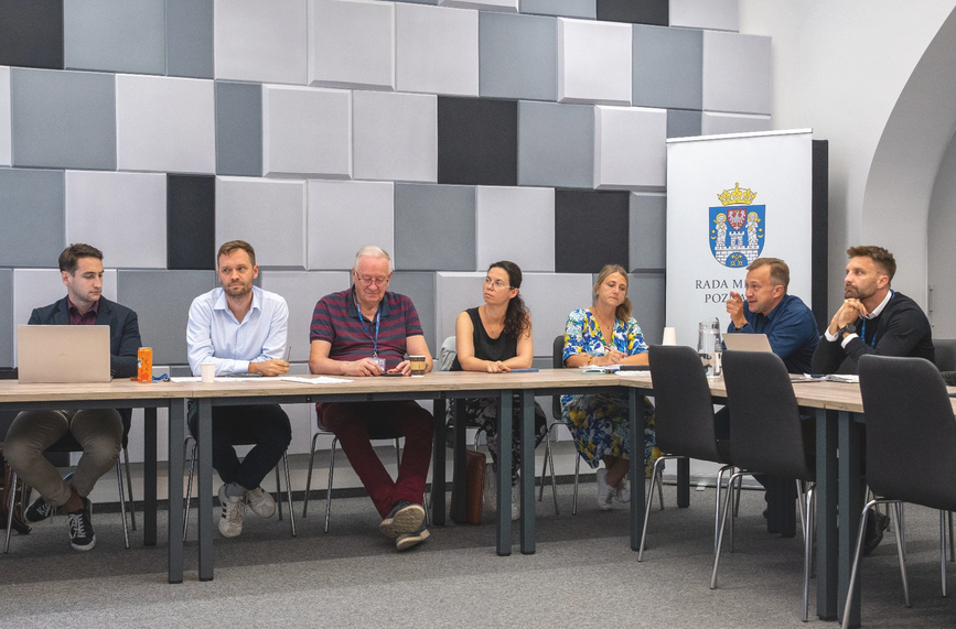 za stołem konferencyjnym siedzi kilkoro osób