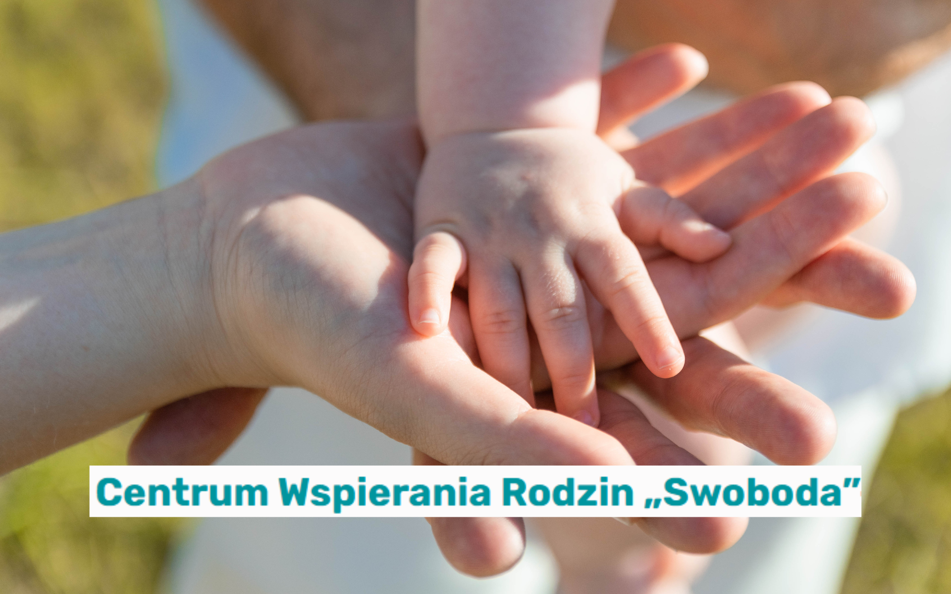 Zbliżenie na dłonie trzech osób - dorosłego, dziecka i niemowlęcia - ułożone jedna na drugiej w geście wsparcia i opieki. W tle rozmyte naturalne otoczenie. Na dole grafiki widoczny jest napis: "Centrum Wspierania Rodzin "Swoboda' zaprasza do skorzystania z bogatej oferty wsparcia dla rodzin zastępczych!".