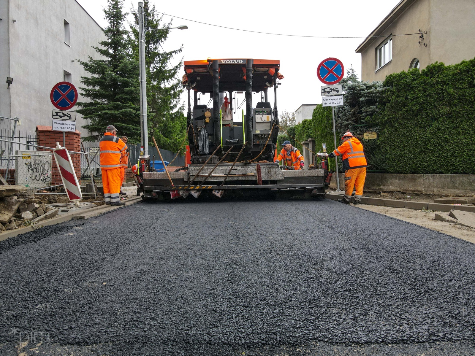 Zdjęcie prac przy układaniu nowej nawierzchni. Widać pracowników i wielką maszynę