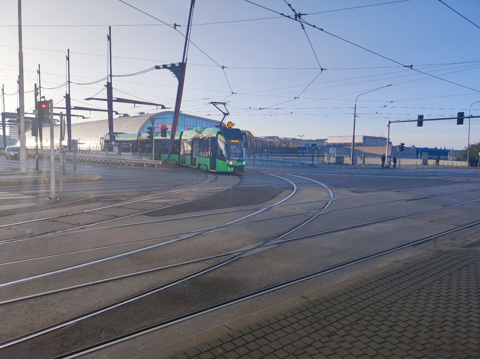 Zdjęcie predstawia jadący z oddali tramwaj numer 10 na tle Dworca Głównego w Poznaniu